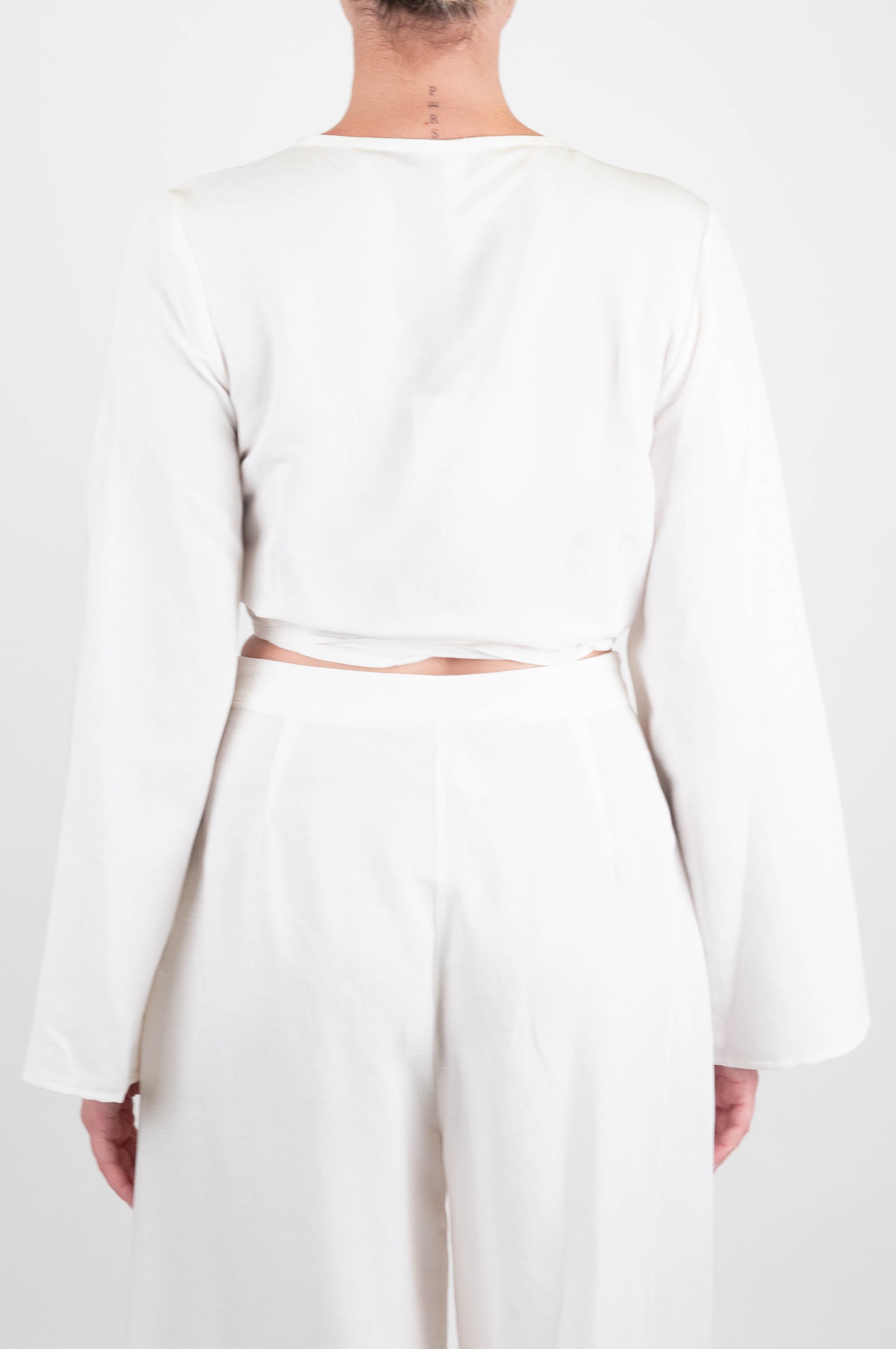 Tensione in - Blusa crop a portafoglio in misto lino con spilla fiore